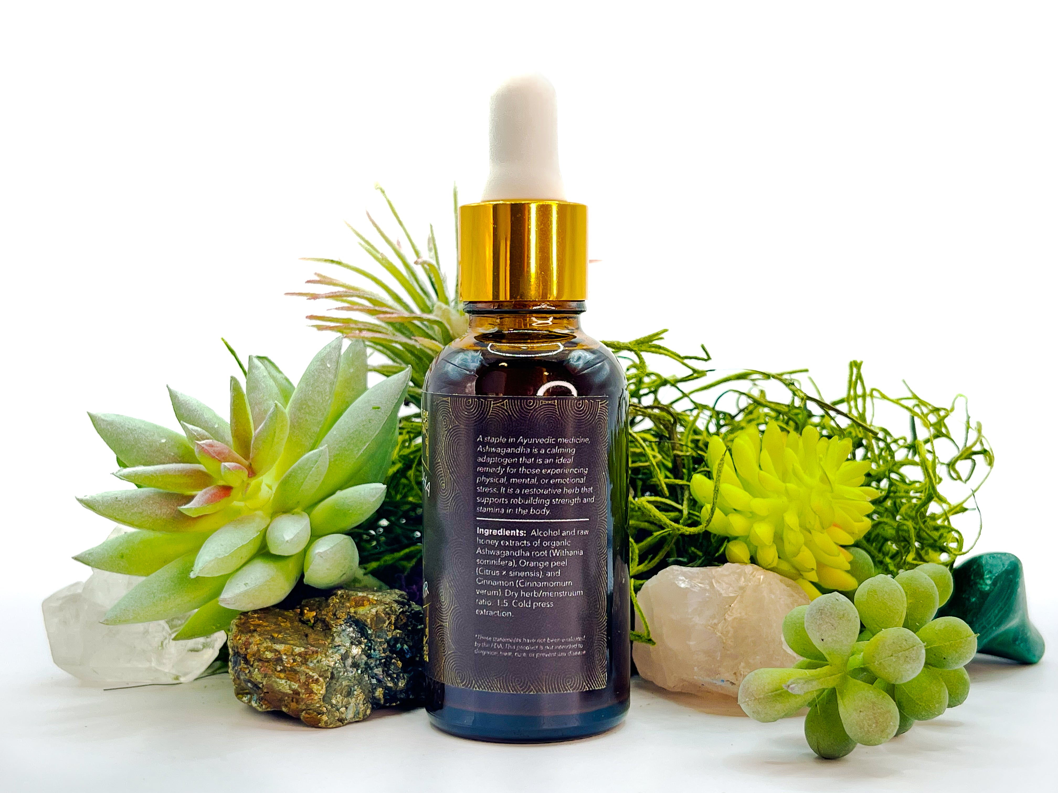 Image of 1 oz bottle of Organic Ashwagandha Orange Elixir by LaLumi Herbes with dropper surrounded by green plants and stones on a white background