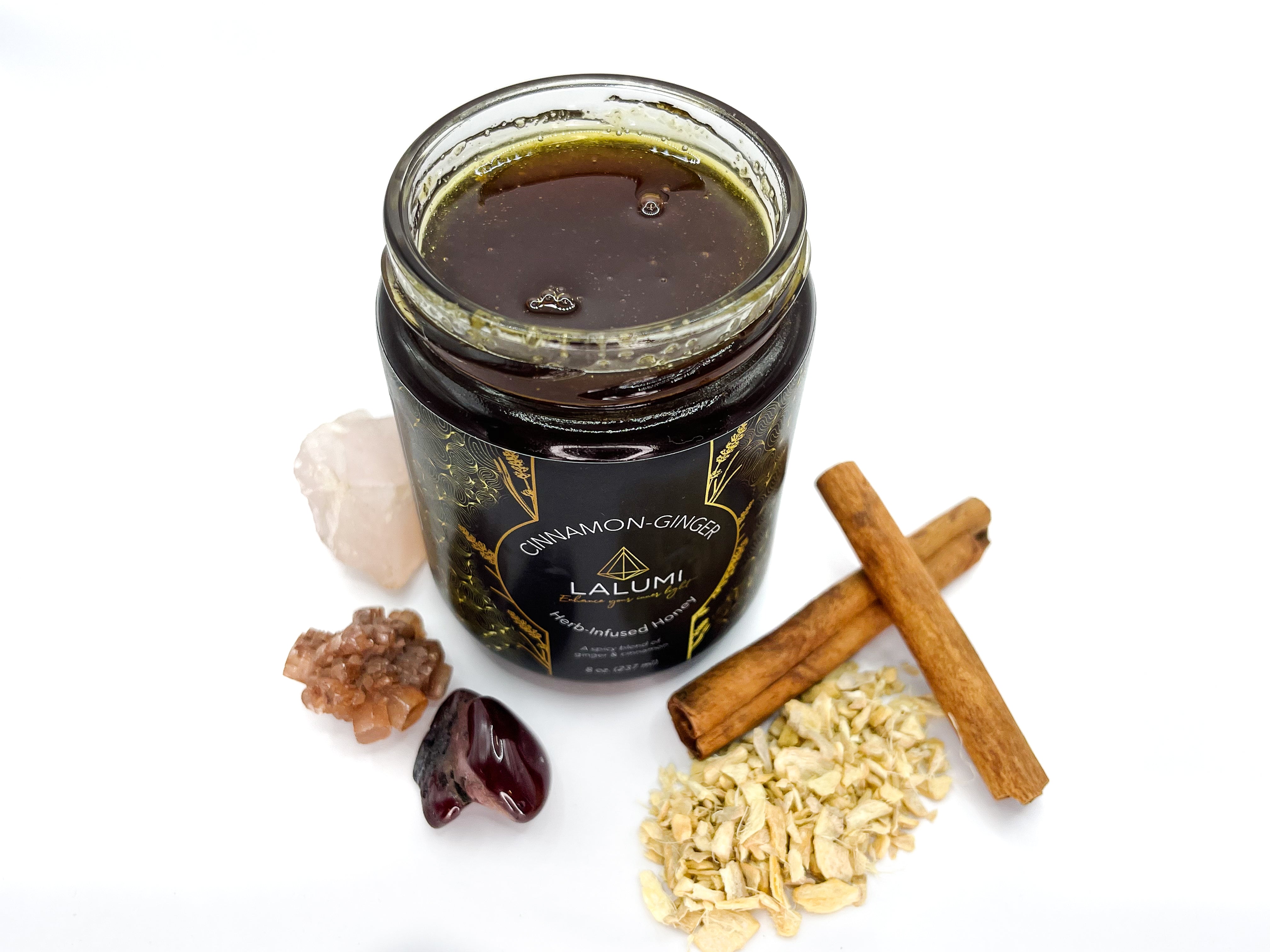 Image of Top view of 8 oz jar of Organic Cinnamon-Ginger Infused Local Honey by LaLumi Herbescinnamon sticks, ginger, and crystals on a white background