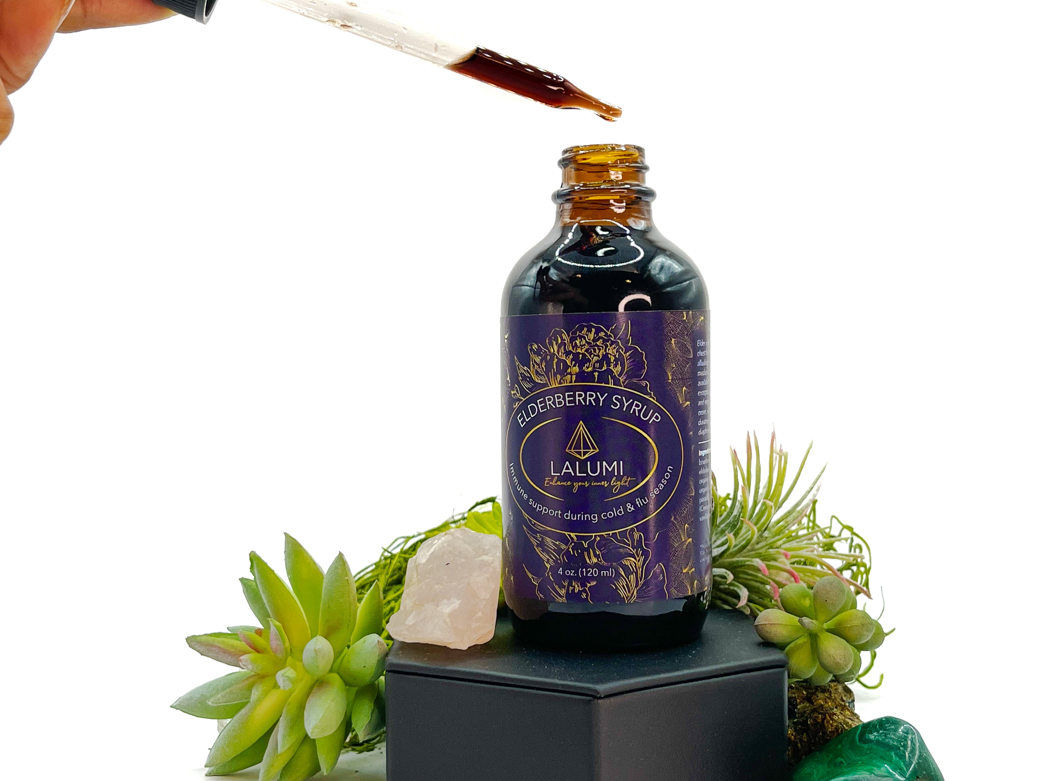 Image of 4 oz bottle of Elderberry Syrup by LaLumi Herbes with a dropper and crystals on a white background