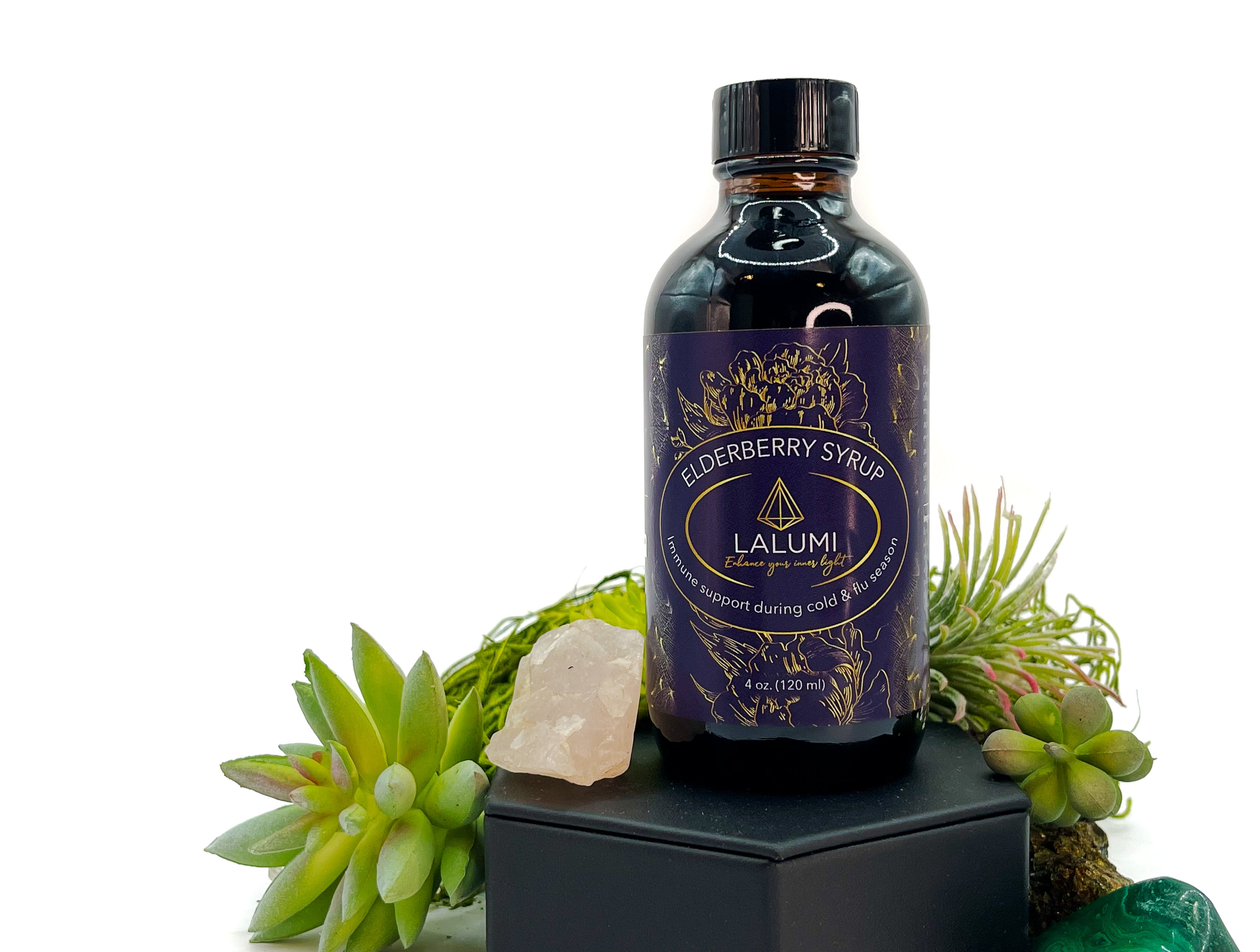 Image of 4 oz bottle of Elderberry Syrup by LaLumi Herbes with decorative plants on a white background, elevated