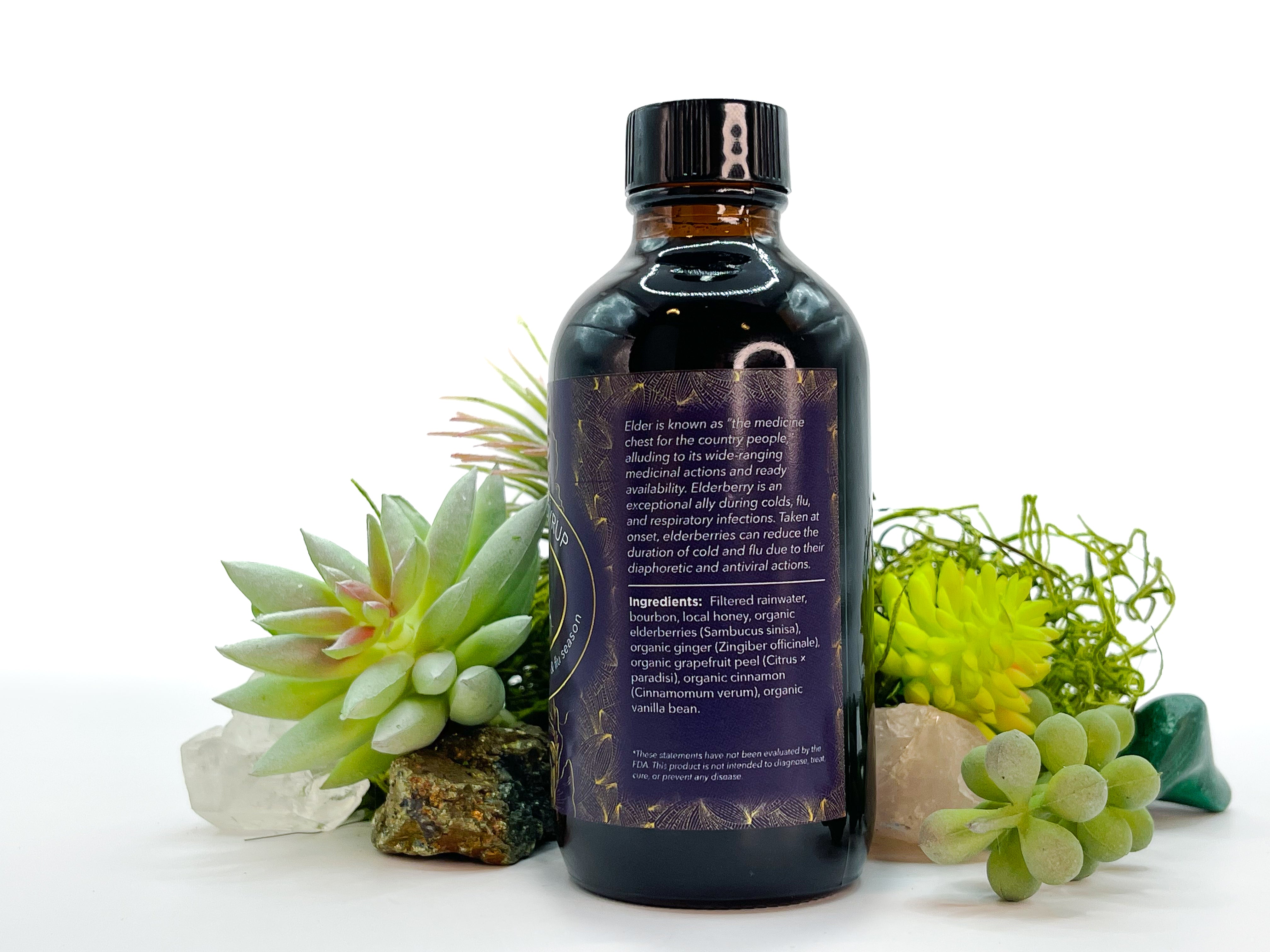 Image of 4 oz bottle of Elderberry Syrup by LaLumi Herbes, side view, on a white background with succulents
