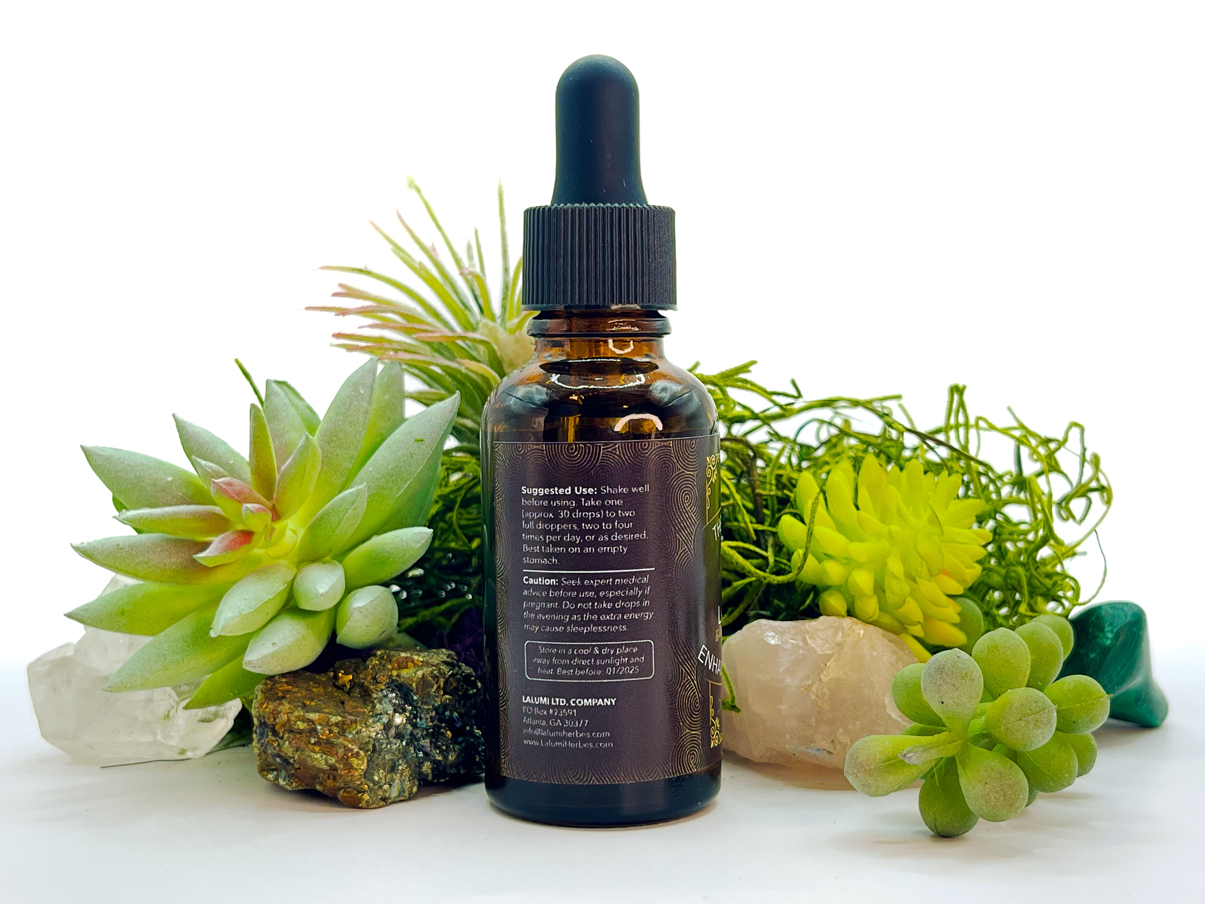 Image of 1 oz bottle of Energy-Enhancing Herbal Tonic by LaLumi Herbes surrounded by succulents and crystals on a white background