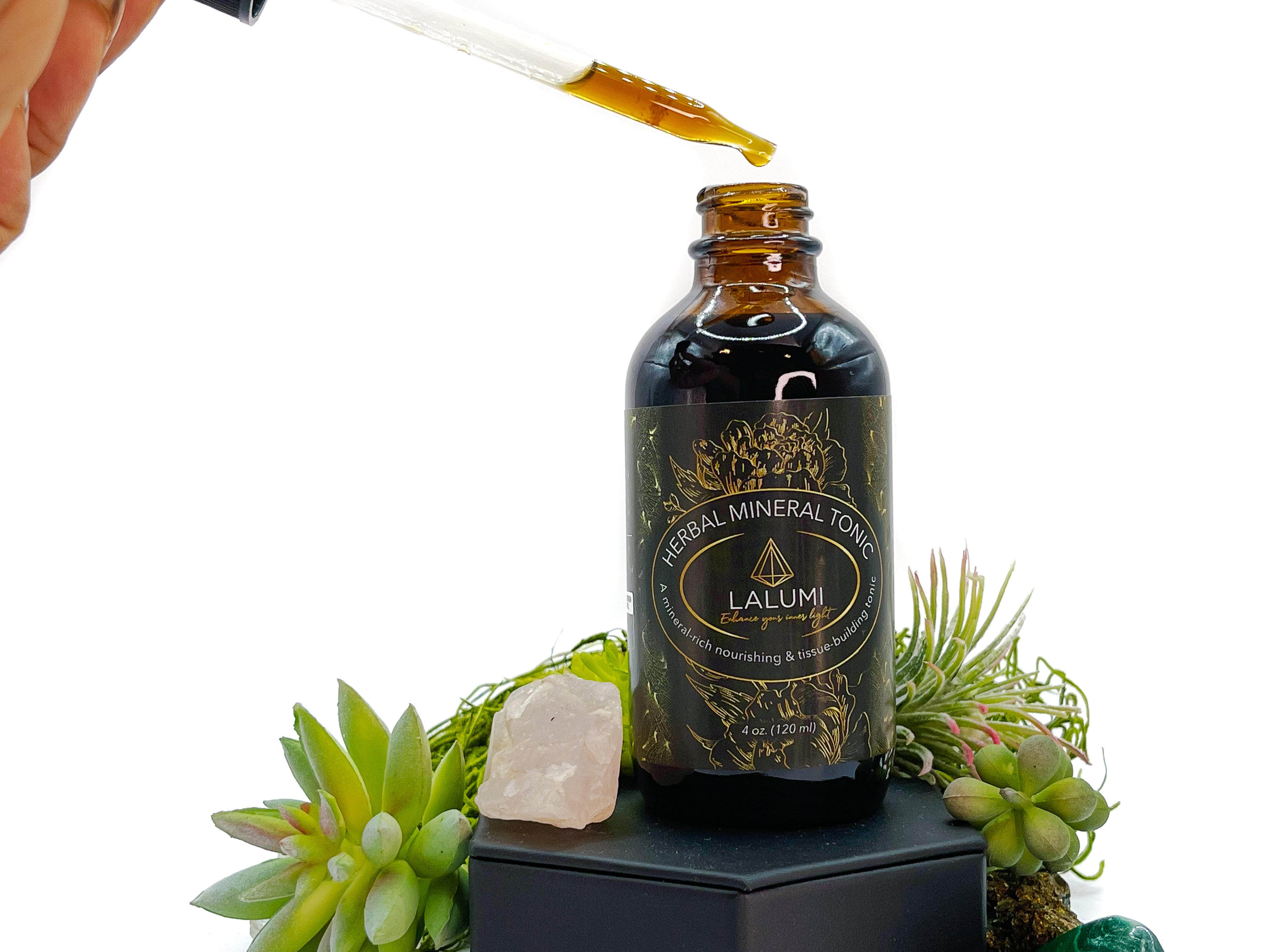 Image of 4 oz bottle of Herbal Mineral Tonic by LaLumi Herbes with a dropper and decorative elements on a white background