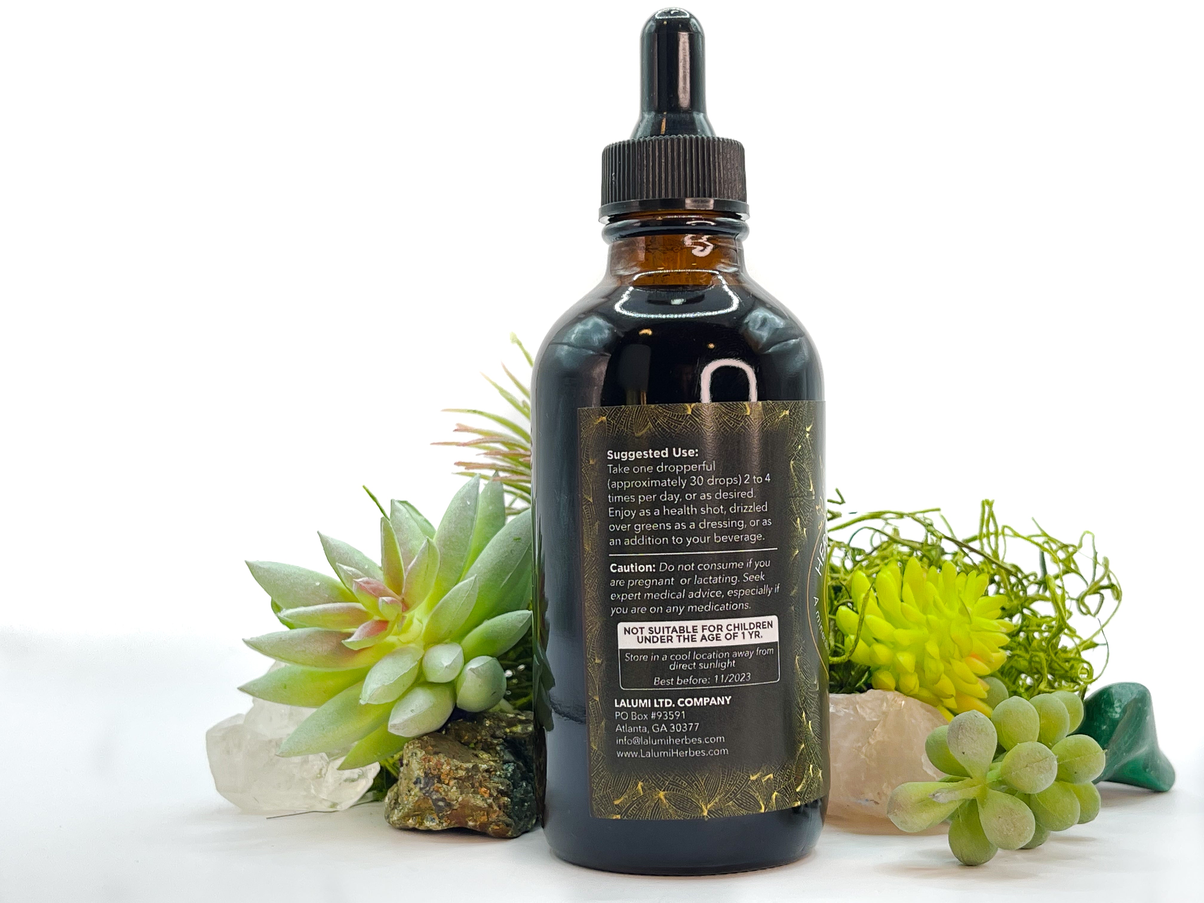 Image of 4 oz bottle of Herbal Mineral Tonic by LaLumi Herbes, side view, with succulents on a white background.