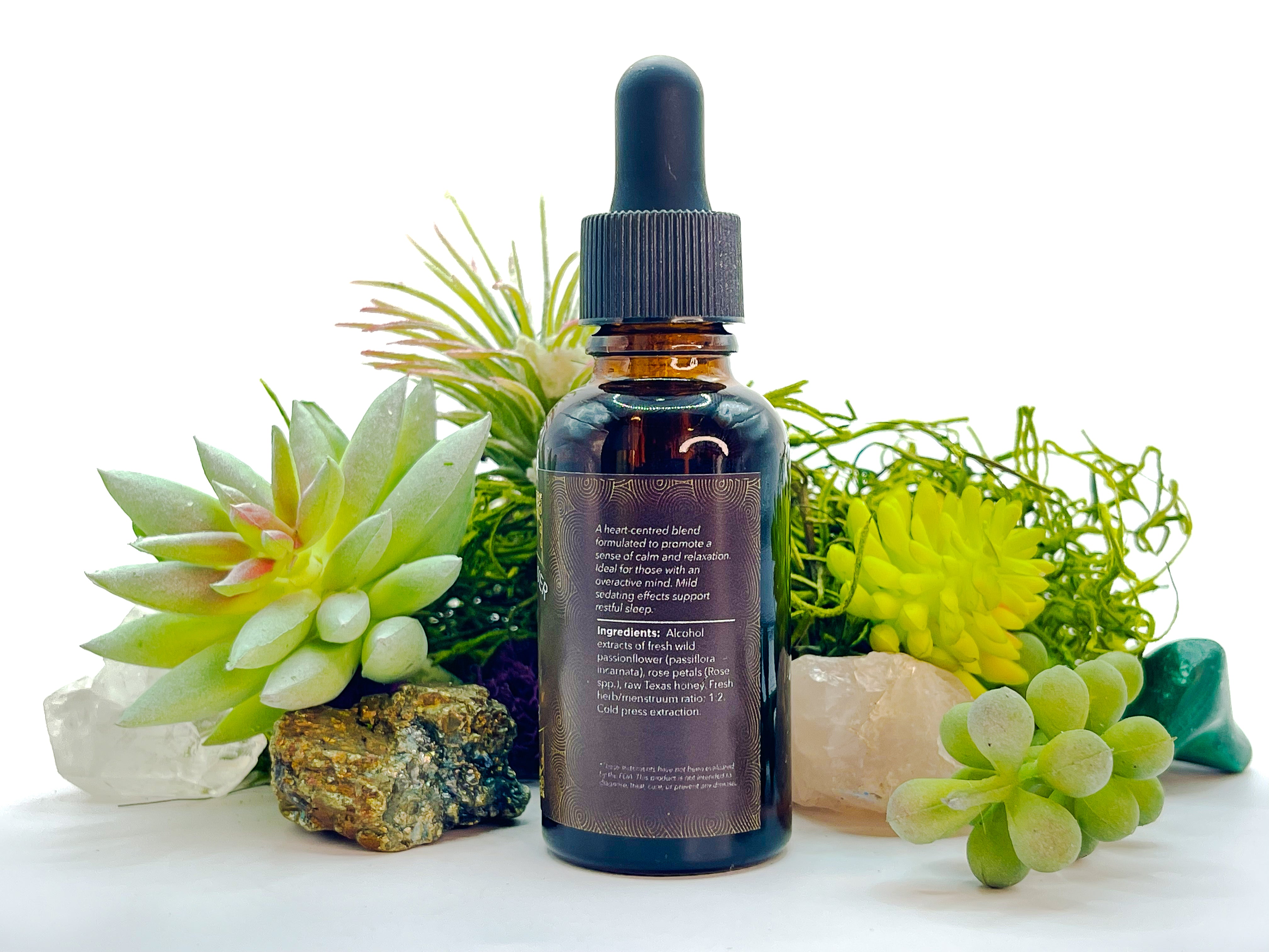 Image of 1 oz bottle of Wildcrafted Passionflower-Rose Herbal Elixir by LaLumi Herbes with succulents and crystals on a white background